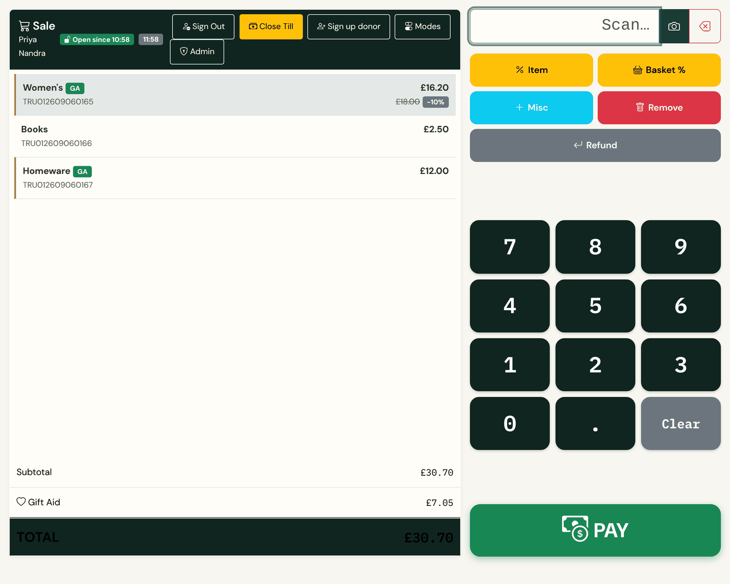 The KindStock till with a three-item basket: a women's clothing line marked down 10% with its £18.00 ticket price struck through, green GA chips on the two Gift Aid lines, a £7.05 Gift Aid line under the subtotal, and the keypad and PAY button on the right.